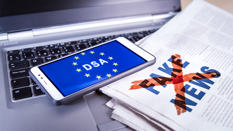 smartphone con scritta DSA giornale con scritto Fake news sopre pc portatile